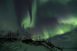 The solar wind moving through the magnetosphere alters the movements of charged particles in the Earth's thermosphere or exosphere, and the resulting ionization of these particles causes them to emit light of varying colour, thus forming auroras near the polar regions.